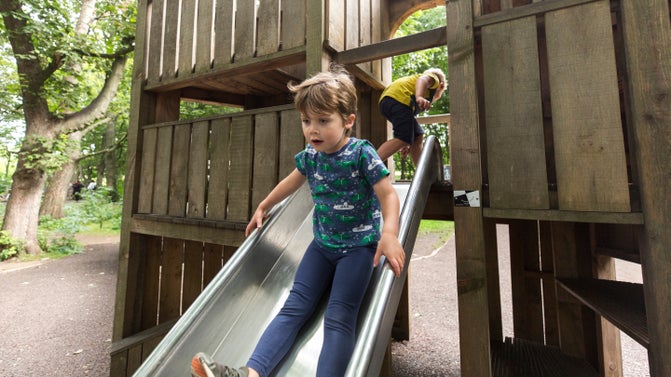 Child goes down the slide, part of a wooden fort in the Delaval Playdium